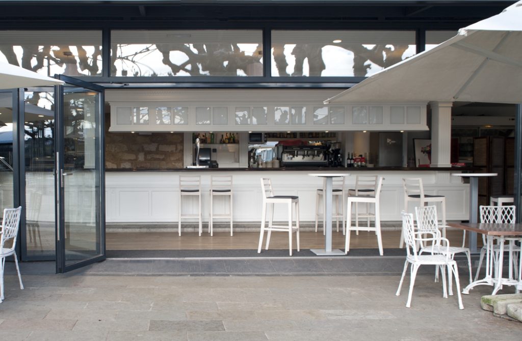 Interior cafeteria con diseño cerramiento de cristal a terraza que se puede abrir completamente, en Club Jolaseta de Neguri - Getxo (Bizkaia)