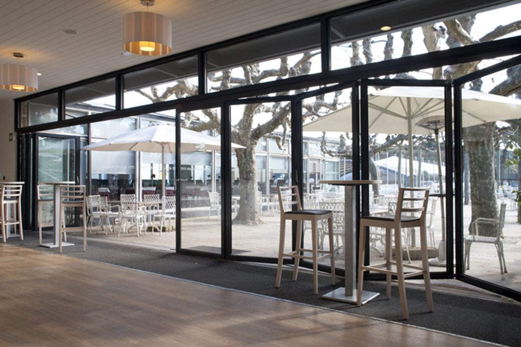 Interior cafeteria con diseño cerramiento de cristal a terraza que se puede abrir completamente, en Club Jolaseta de Neguri - Getxo (Bizkaia)